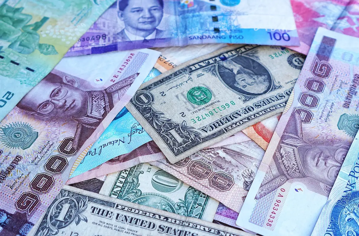 A mix of international banknotes — US dollars, Thai baht, Philippine pesos, Indonesian rupiah